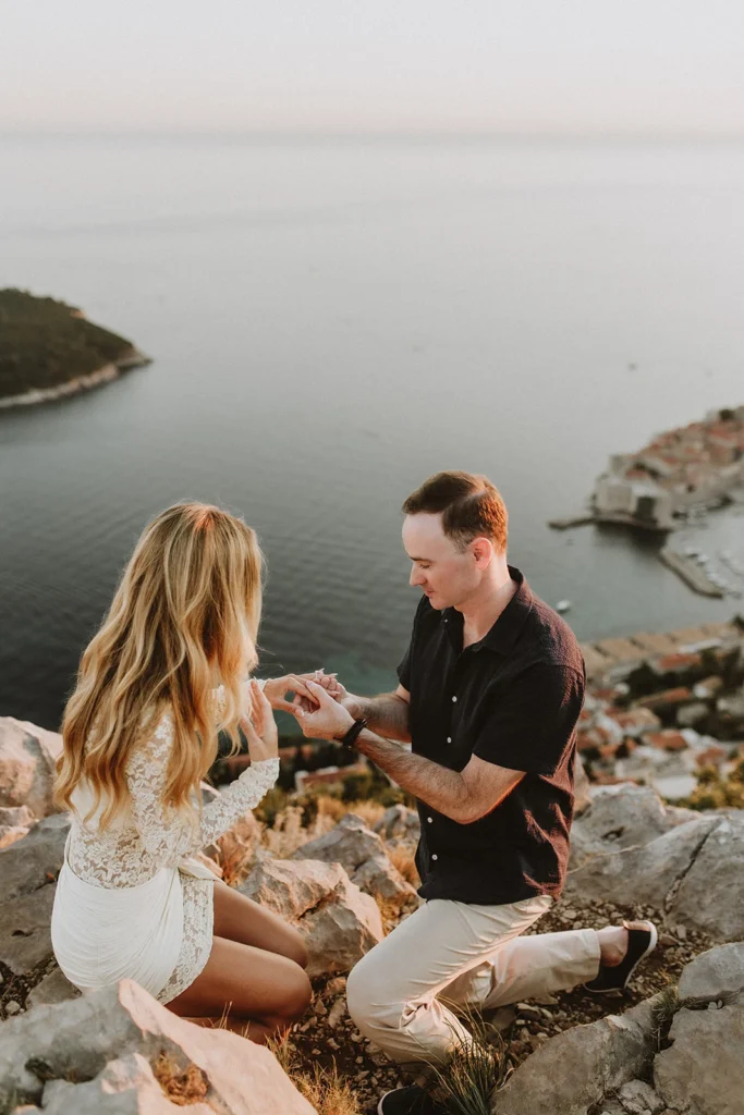 guy putting an engagement ring to his girlfriend hands